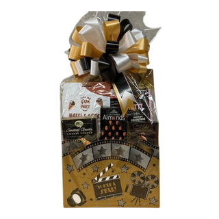 A gift basket adorned with a movie-themed decoration, including items such as Pretzels, Popcorn, and Chocolate covered treats, wrapped in a gold and black color scheme with a bow.